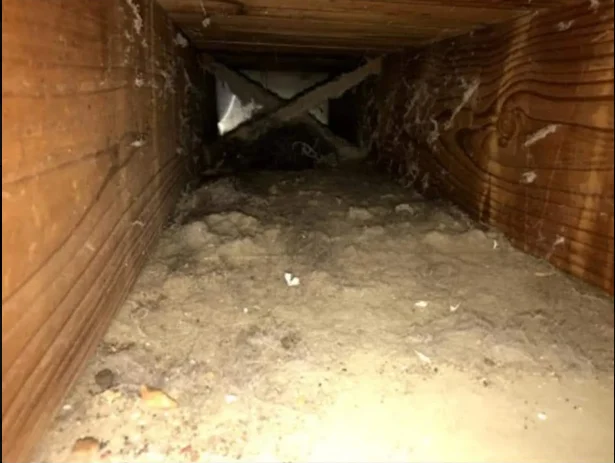 Interior of air duct with dust and debris accumulation on walls and floor