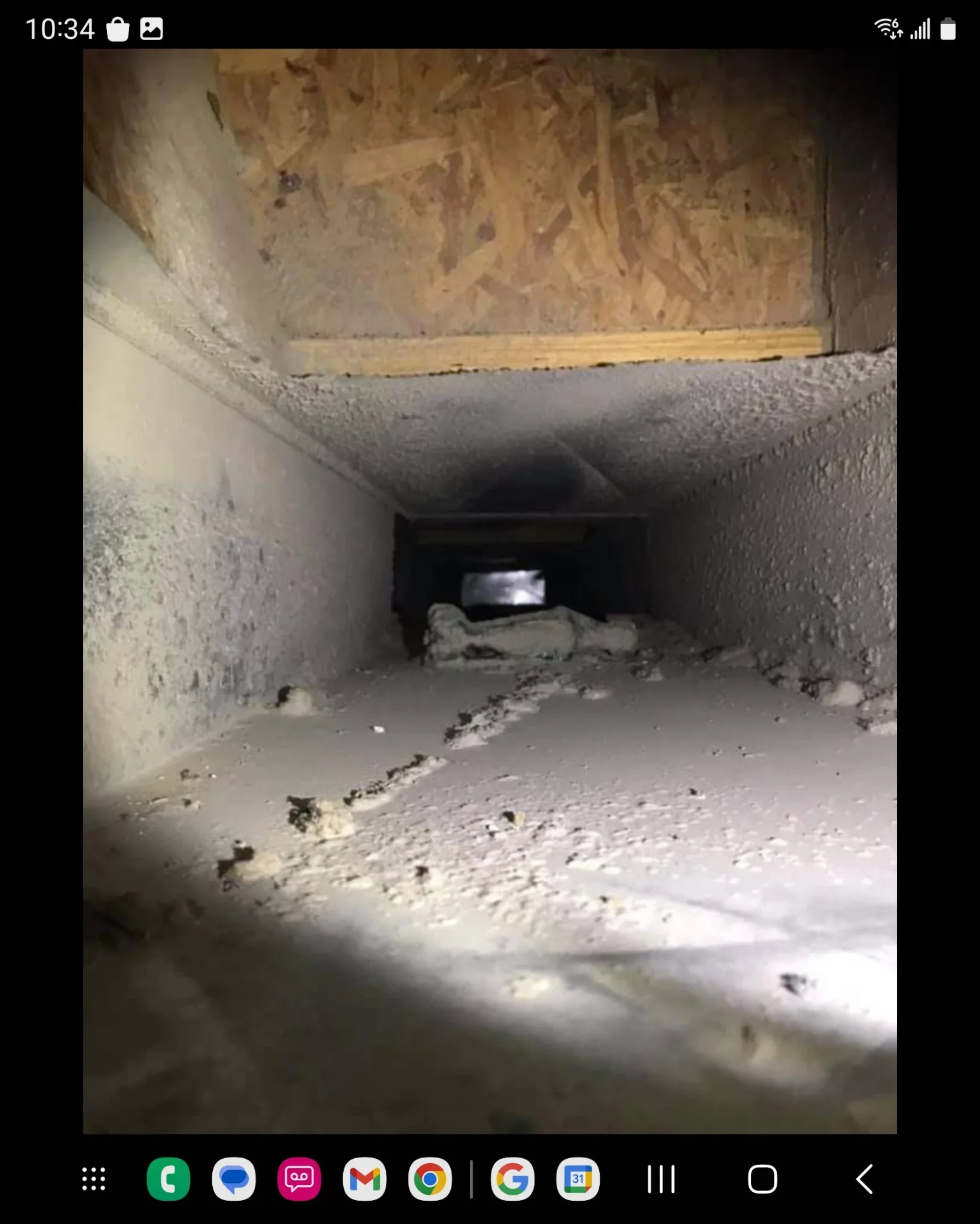 Interior air duct with dust and debris buildup on concrete surfaces and framing