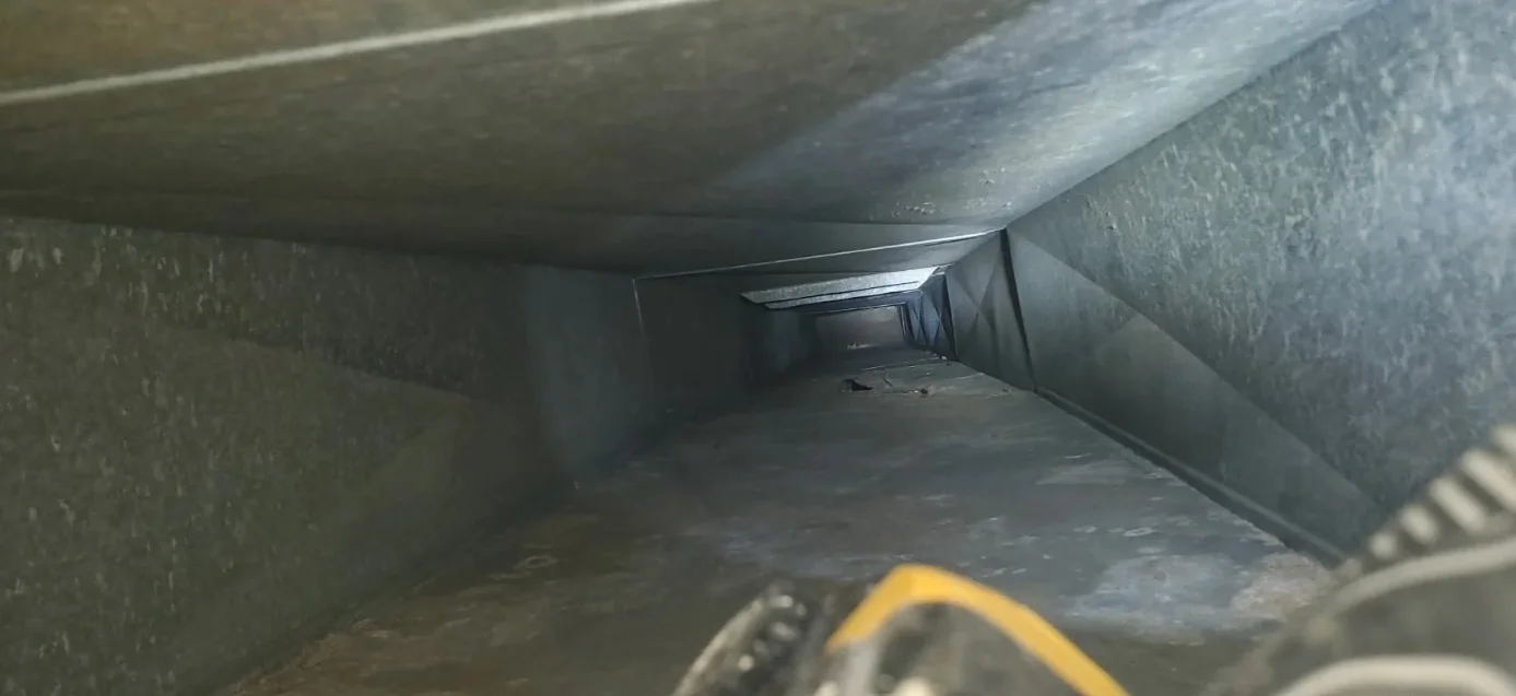 Interior air duct with dust and debris buildup on metal ductwork walls