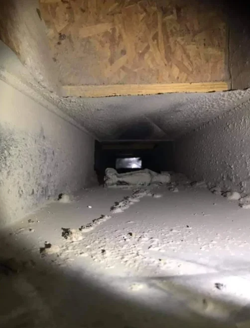 Interior of air duct with dust and debris accumulation on concrete surfaces